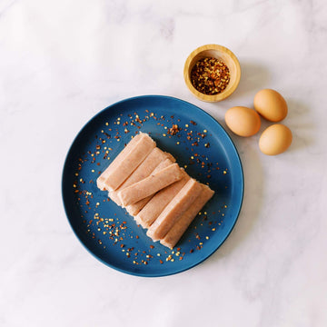 Pasture-raised pork sausage links with red pepper flakes on a blue plate