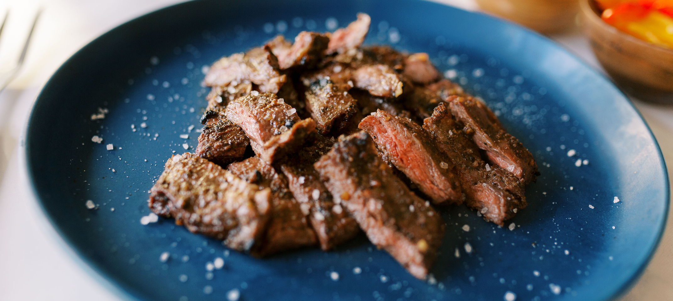 Sliced cooked Pasture-raised steak on a blue plate